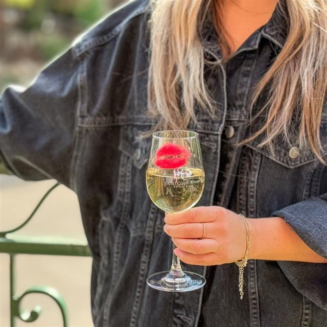 A woman holding a wine of glass with lipstick marks on it